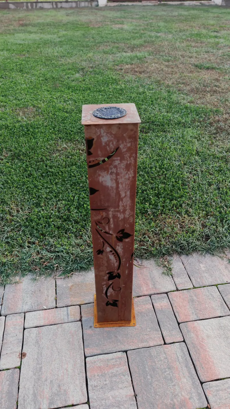 La lampada vista di fronte sul prato, con il decoro a edera sulla lamiera