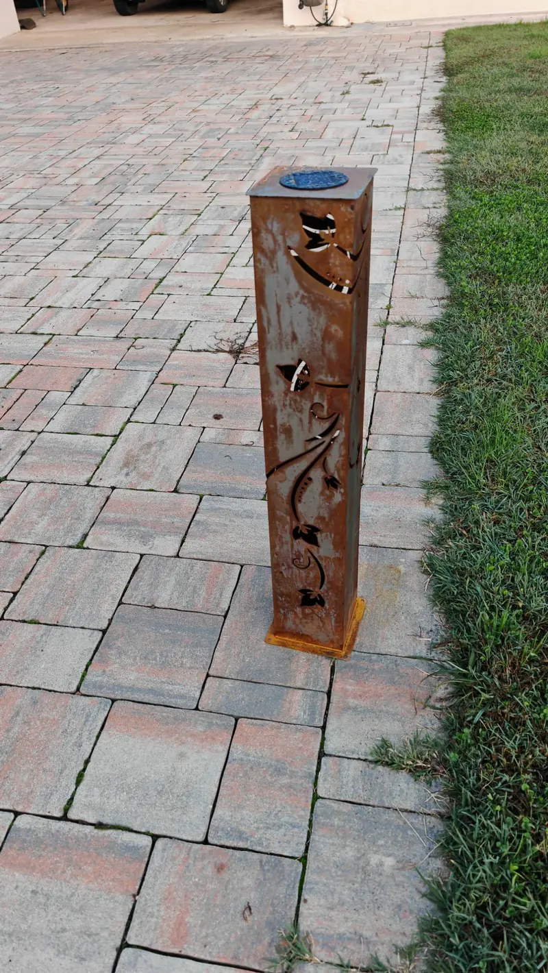 La lampada su un viale in pietra, vista in diagonale di giorno, con il decoro a edera