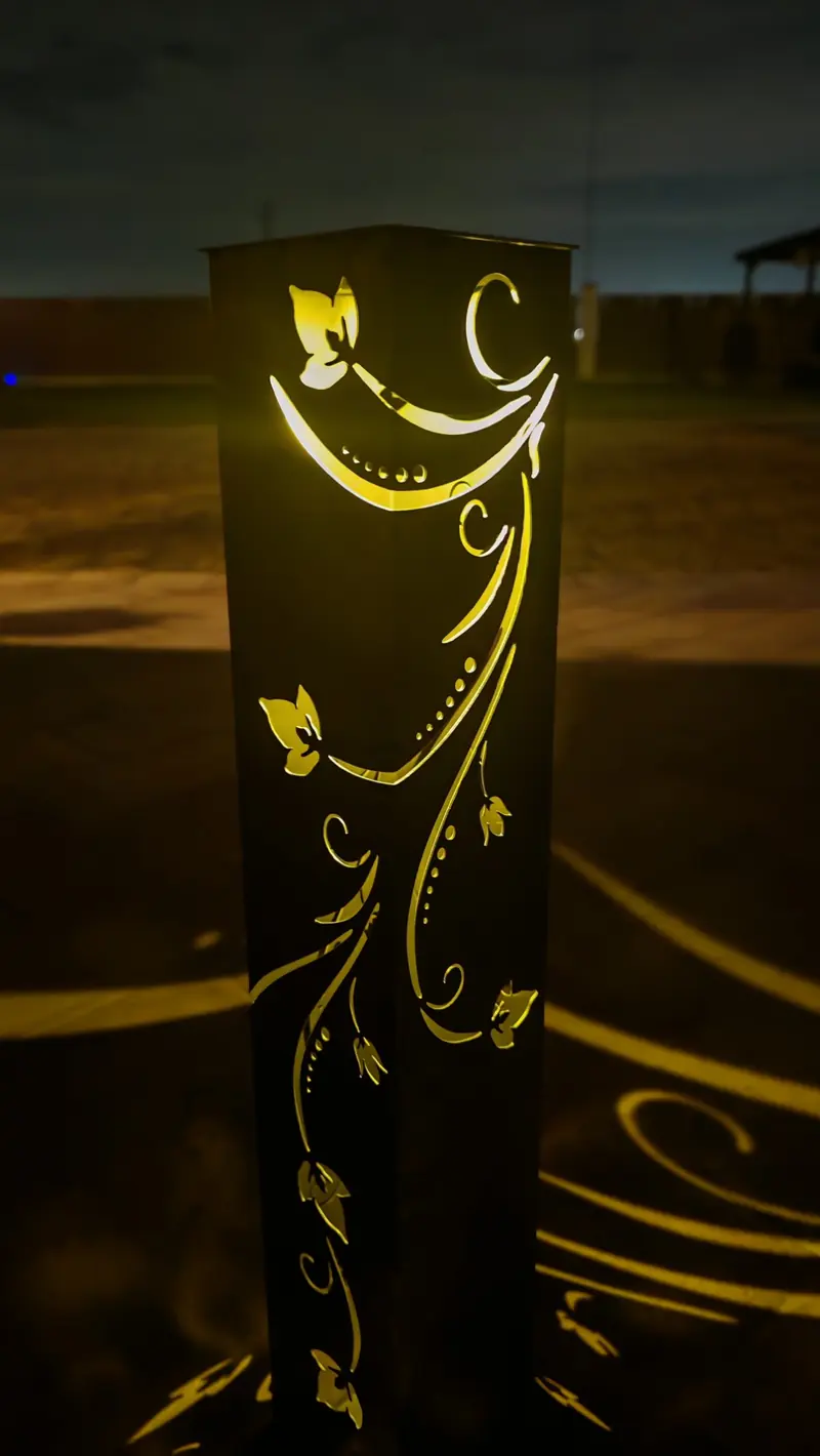 Primo piano della lampada accesa di notte: foglie, volute e puntini del decoro illuminati dall'interno
